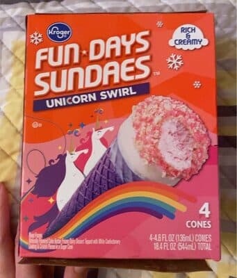 Unicorn Swirl Flavored Cake Batter Frozen Dairy Dessert Topped With White Confectionery Coating & Crunch Pieces In A Sugar Cone